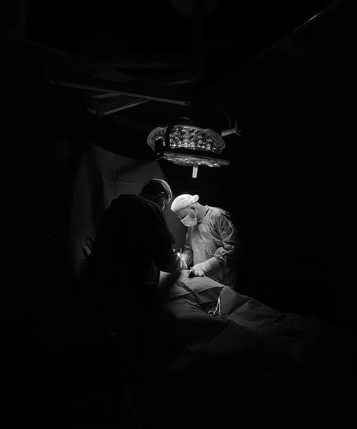 surgeon in dark room performing an operation